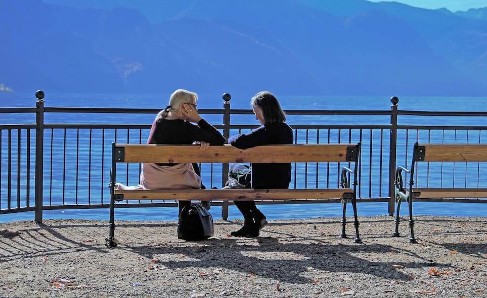 The healing power of listening. Two people sitting on at outdoor bench.